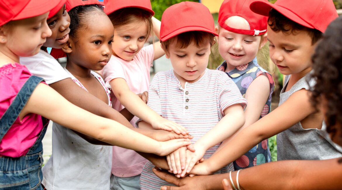 Kinder im Feriencamp legen gemeinsam die Hände aufeinander