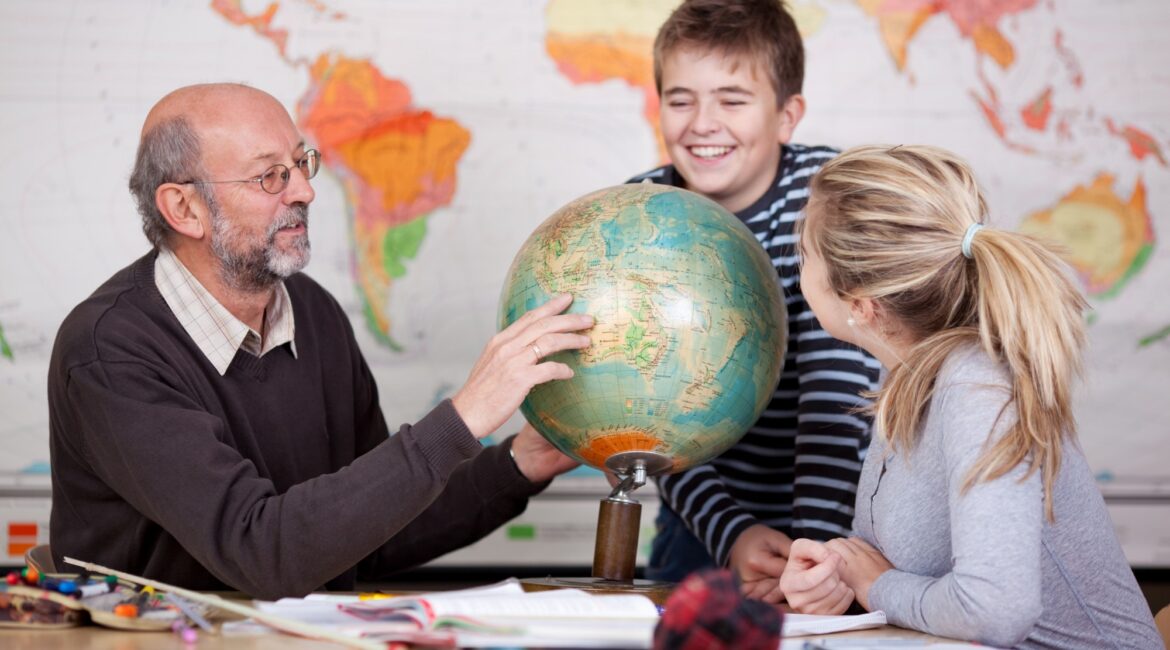 Jugendliche lernen mit Lehrer am Globus